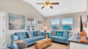 A living room with a blue sofa set, a wooden coffee table, and a ceiling fan.