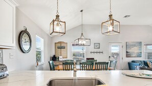 A kitchen with a marble countertop, a sink, and hanging pendant lights.