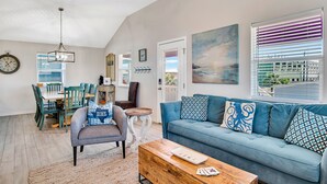 A living room with a blue sofa, a wooden coffee table, and a dining area with a table and chairs.