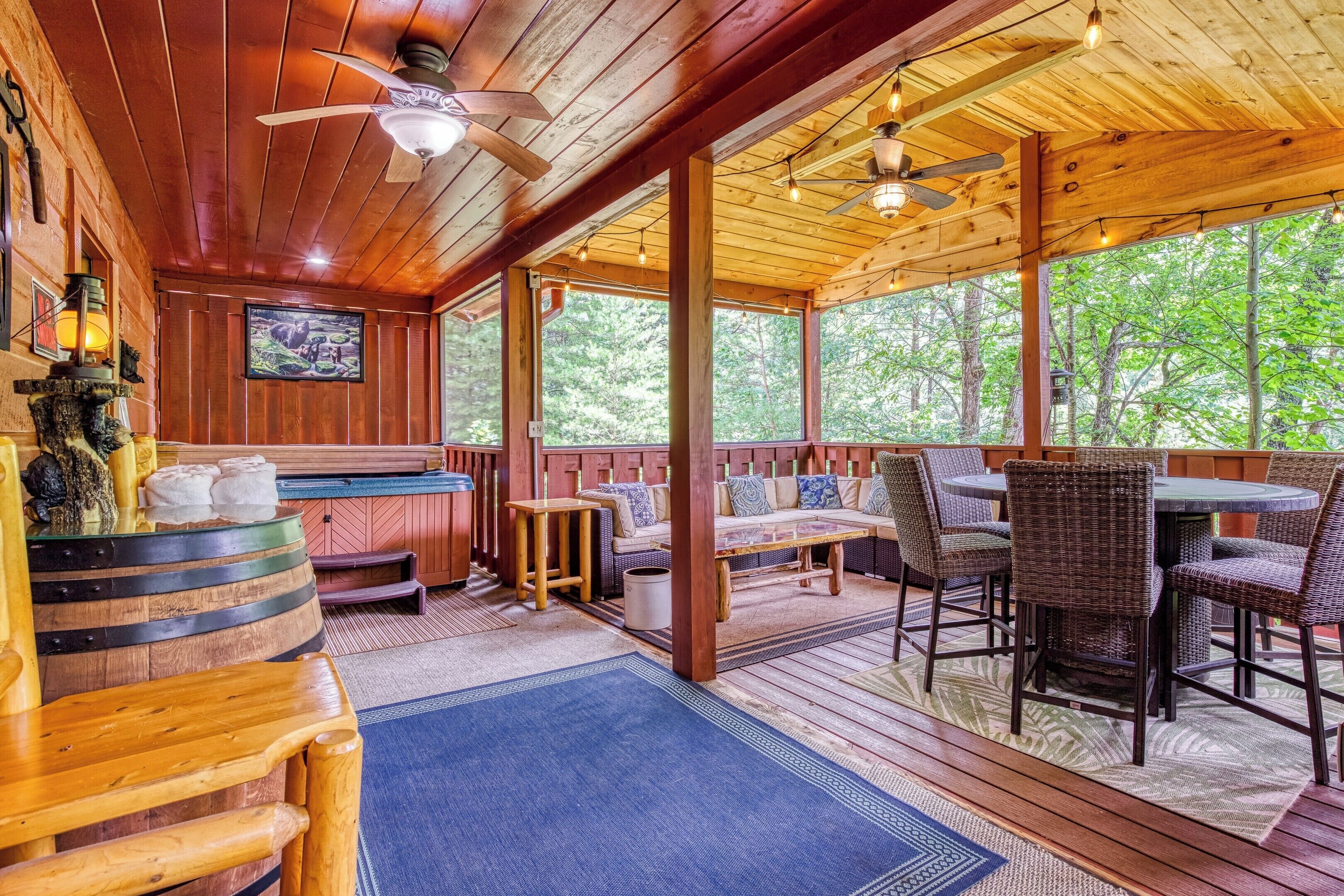A wooden deck with a seating area, a bar, and a ceiling fan.