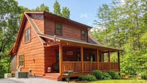 Une cabane en rondins à deux étages, dotée d’un porche et d’un garage.