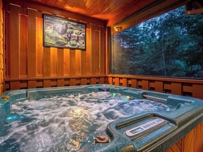 A hot tub with a digital control panel, surrounded by wooden paneling and a large window offering a view of a forest. - MoreDISCOUNTS🌄
COZY PEACEFULSeclusionCLOSE to FUN 2BR+Loft 170+ 5 star Reviews (Sevierville)