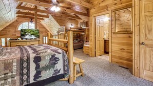 Une chambre confortable dans un chalet en bois, avec un lit superposé, un bureau et une fenêtre donnant sur une forêt.