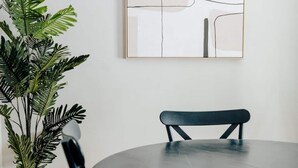 A dining area with a round table, black chairs, a potted plant, and a framed abstract artwork on the wall. - Chic 2BR Stay | Cozy Living & High-Speed WiFi (Montgomery)
