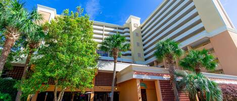A hotel with a modern architectural design, featuring a central courtyard with palm trees and a variety of plants.