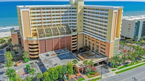 A multi-story hotel with a rooftop pool, surrounded by palm trees and a view of the ocean. - BEACHFRONT DIRECT OCEANFRONT PENTHOUSE ONTHE GOLDEN MILE MYRTLE BEACH GRANSTRAND (Myrtle Beach)