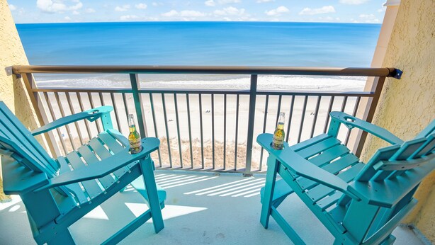 A balcony with turquoise chairs and a bottle of Corona beer, overlooking a beach with a clear blue sky. - BEACHFRONT DIRECT OCEANFRONT PENTHOUSE ONTHE GOLDEN MILE MYRTLE BEACH GRANSTRAND (Myrtle Beach)