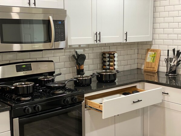 A modern kitchen with stainless steel appliances, white cabinetry, and a black countertop. - Conveniently Located close to the City Center (Marietta)
