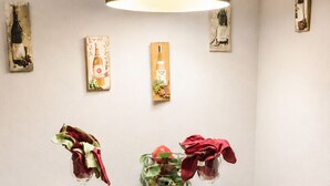 Une table à manger avec deux chaises, un luminaire suspendu et des œuvres d’art accrochées au mur.