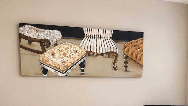 Une chambre à coucher avec un lit, des oreillers, une télévision, une table de chevet et une œuvre d’art murale.