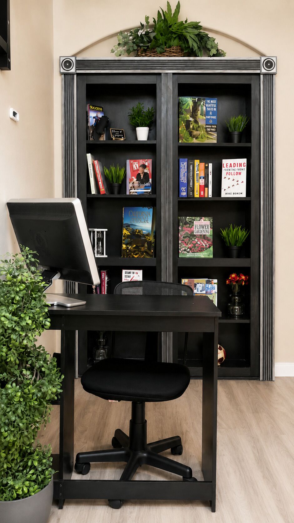 A workspace with a desk, chair, and a bookshelf containing books and decorative items.