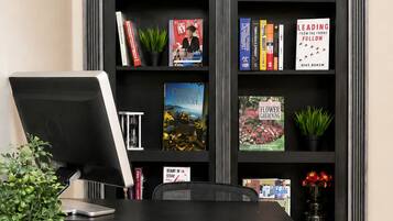 A workspace with a desk, chair, and a bookshelf containing books and decorative items.