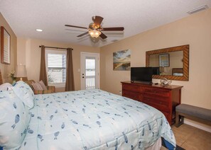 A bedroom with a bed, a dresser, a television, a ceiling fan, and a window with blinds.