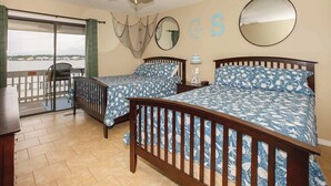 A bedroom with two beds, a ceiling fan, and a view of the water.