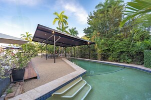 Una piscina al aire libre, sombrillas, sillones reclinables de piscina