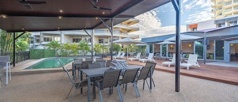 An outdoor patio area with a pool, lounge chairs, and a covered seating area.