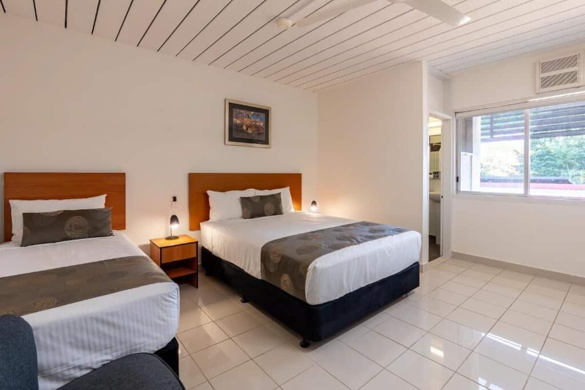 Habitación de hotel con dos camas, una mesita de noche, un cuadro en la pared y una ventana con vistas.