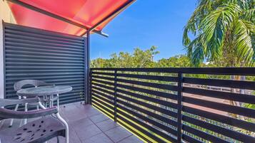 A balcony with a red awning, metal railing, and a table with chairs.