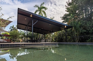 Una piscina al aire libre, sombrillas, sillones reclinables de piscina