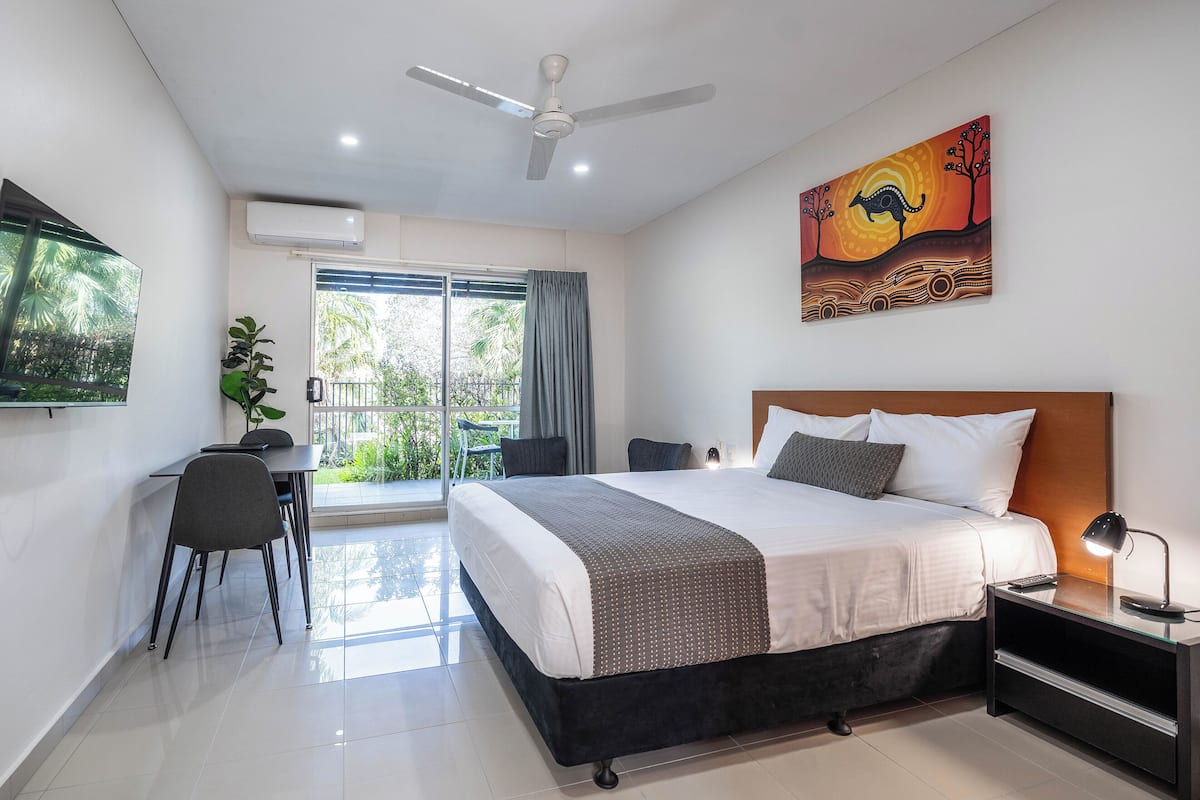 Una habitación de hotel moderna con cama, escritorio, silla y un cuadro en la pared.