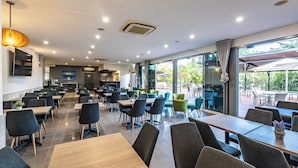 Un ristorante moderno con posti a sedere interni ed esterni, ampie vetrate e un'atmosfera informale.
