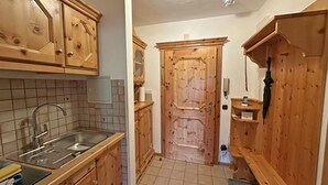 Eine Küche mit Holzausstattung, einer gefliesten Spritzschutzwand, einem Spülbecken und einer Tür zu einem anderen Raum.