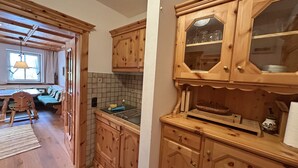 Eine Holz-Küche mit Essbereich, ausgestattet mit Schränken, einer Fliesenküchenzeile und einem Fenster mit Vorhängen.