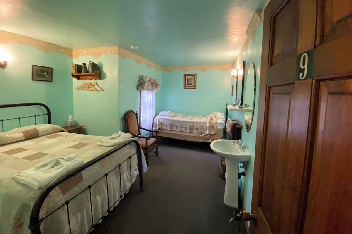 A room with two beds, a chair, a sink, and a door marked with the number 9.