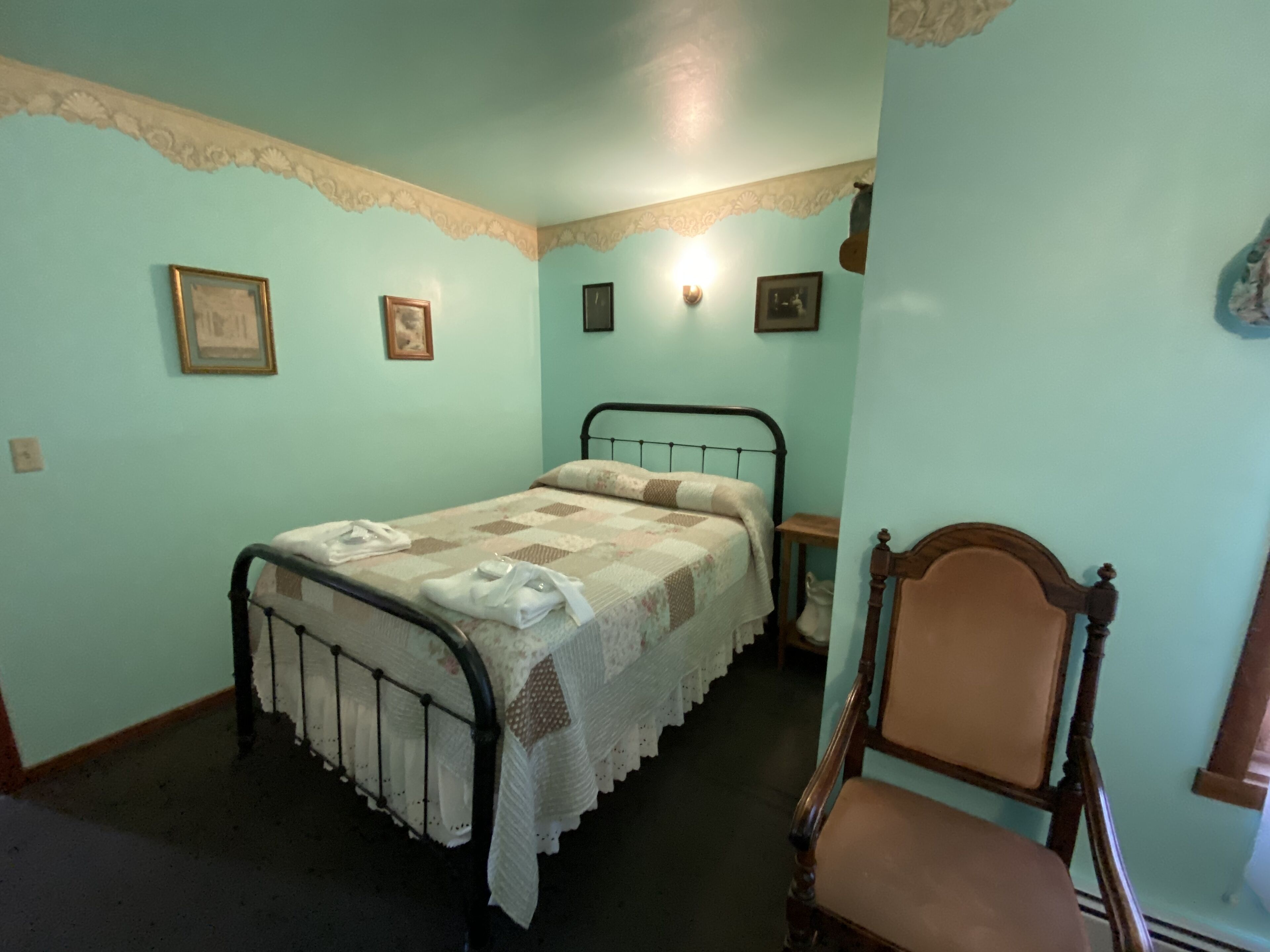 Une chambre avec un lit simple, une chaise en bois et une petite table.