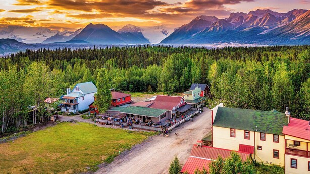 A small town with a central building surrounded by a forest, with mountains in the background. - McCarthy Lodge Resort (McCarthy)