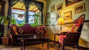 A room with a sofa, armchair, and table, with a view of mountains through a window. - McCarthy Lodge Resort (McCarthy)