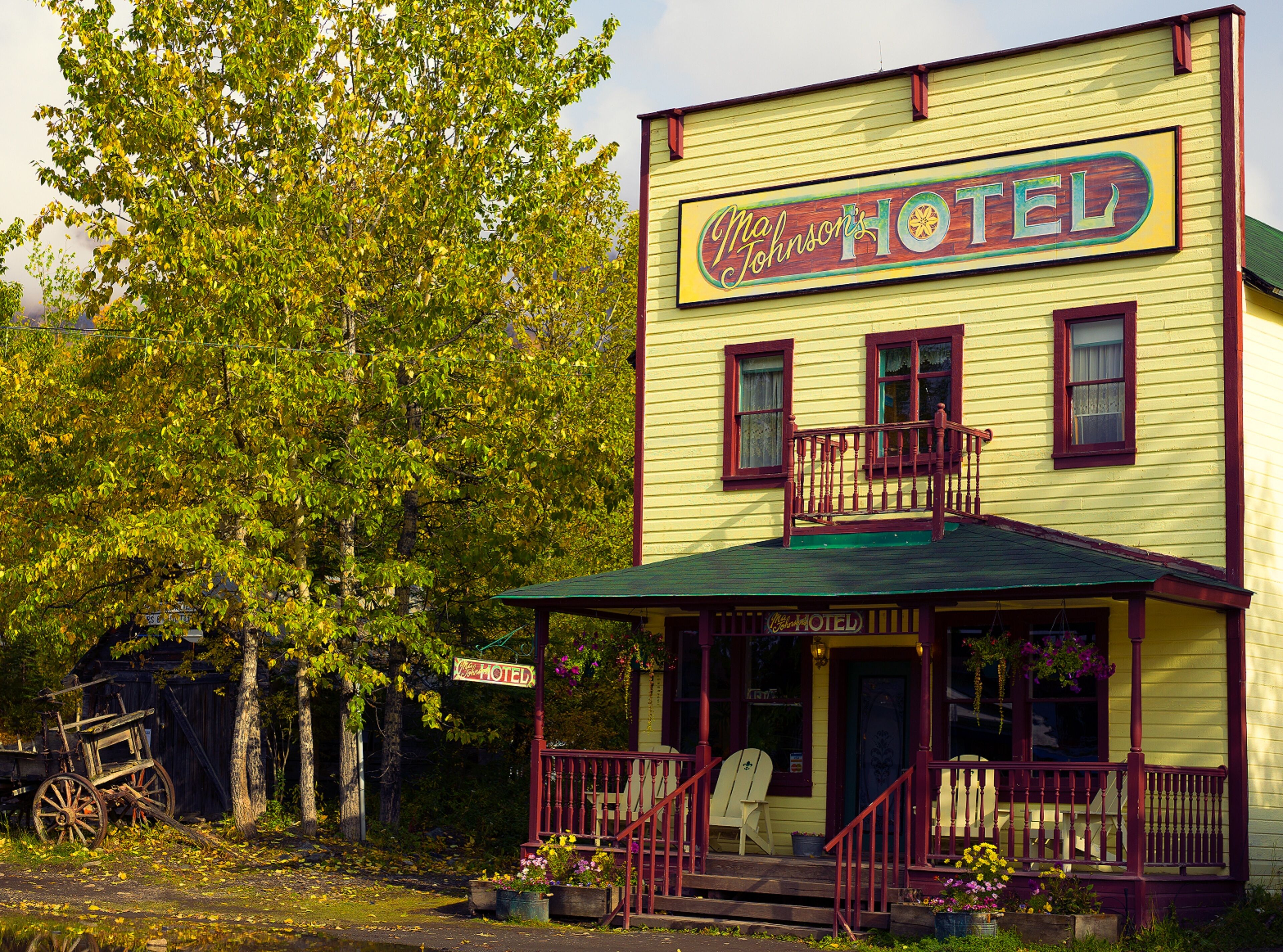 A yellow building with a sign reading "Ma Johnson's Hotel" and a porch with a red railing.