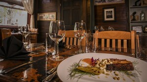 A dining table set with plates, glasses, and cutlery, featuring a dish with meat and vegetables. - McCarthy Lodge Resort (McCarthy)