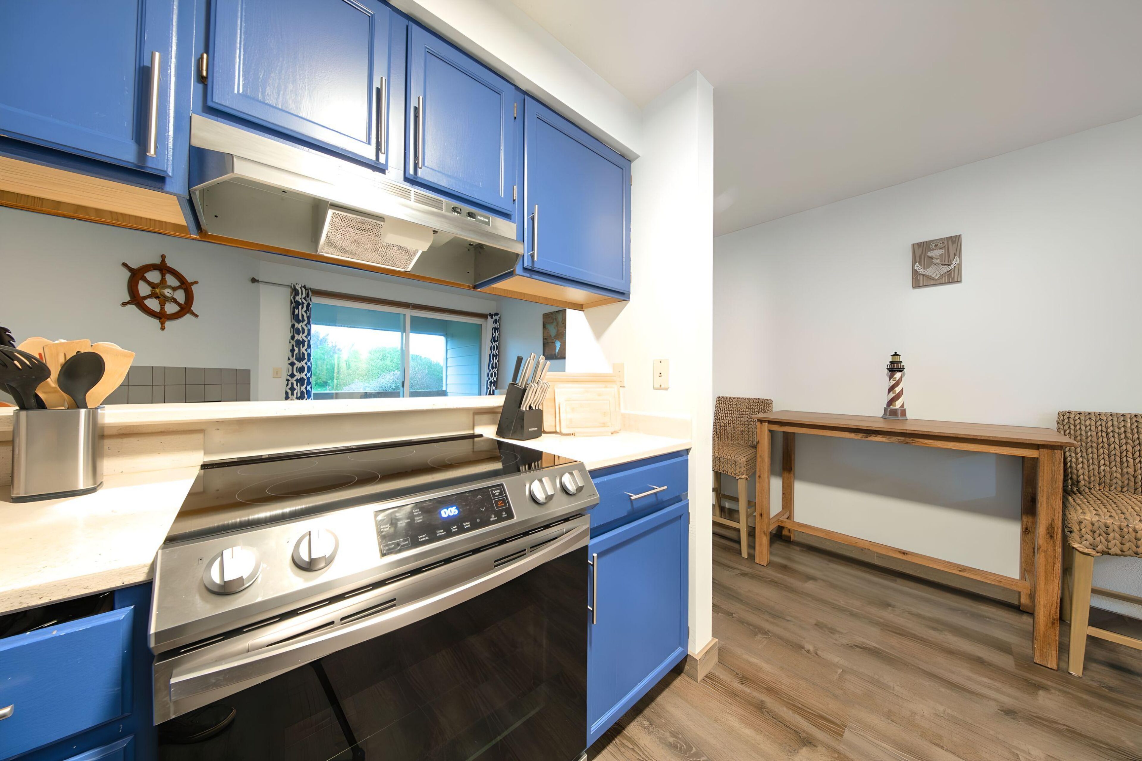 Una cocina con armarios azules, una estufa de acero inoxidable y una mesa de comedor de madera.