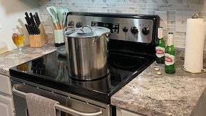 Een keuken met een roestvrijstalen kookplaat, een pan op het fornuis, een wijnglas en Stella Artois bierflesjes.