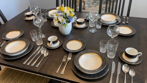 Een eettafel gedekt met borden, glazen, bestek en een vaas met bloemen.