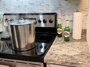 A kitchen with a stainless steel stove, a pot on the burner, and two bottles of Stella Artois beer on the counter.