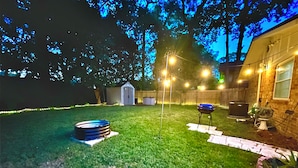 A backyard with a barbecue grill, a hot tub, and a shed.