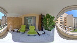 Ein Balkon mit zwei grünen Stühlen, einem kleinen Tisch und einem Blumentopf.