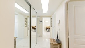Ein Flur mit einem Spiegel, einer hölzernen Bank und einem Essbereich mit Stühlen und einem Tisch.