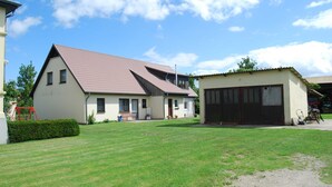 Une maison à deux étages avec un toit en pente, un garage et une pelouse bien entretenue.