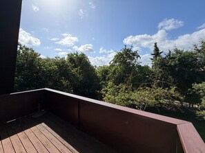 A wooden deck with a view of dense green trees and a clear sky. - FeWo Südwind - Reek, Renate & Reinhold (Insel Poel)