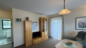 Un salon comprenant un meuble en bois, un téléviseur à écran plat, une table à manger et un canapé.