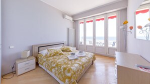 A bedroom with a bed, bedside table, and a view of the sea through large windows. - Wonderful Apartment on Sea (Nice)