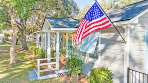 Une maison avec un porche, un drapeau et un petit jardin.