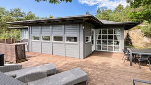 Ein modernes Haus mit Terrasse, eingebauten Sitzgelegenheiten und einem großen Fenster.