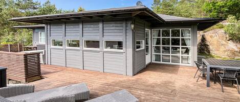 A modern house with a deck, built-in seating, and a large window.