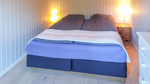 Ein Einzelbett mit blauer und weißer Bettdecke, zwei Kissen und zwei Nachttischlampen.