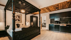 A four-poster bed with intricate carvings, a modern kitchen with dark cabinetry, and a wooden ceiling. - Ferienwohnung - Wagrain (Wagrain)