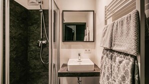 A modern bathroom with a glass-enclosed shower, a white sink, and a mirror above it. - Ferienwohnung - Wagrain (Wagrain)
